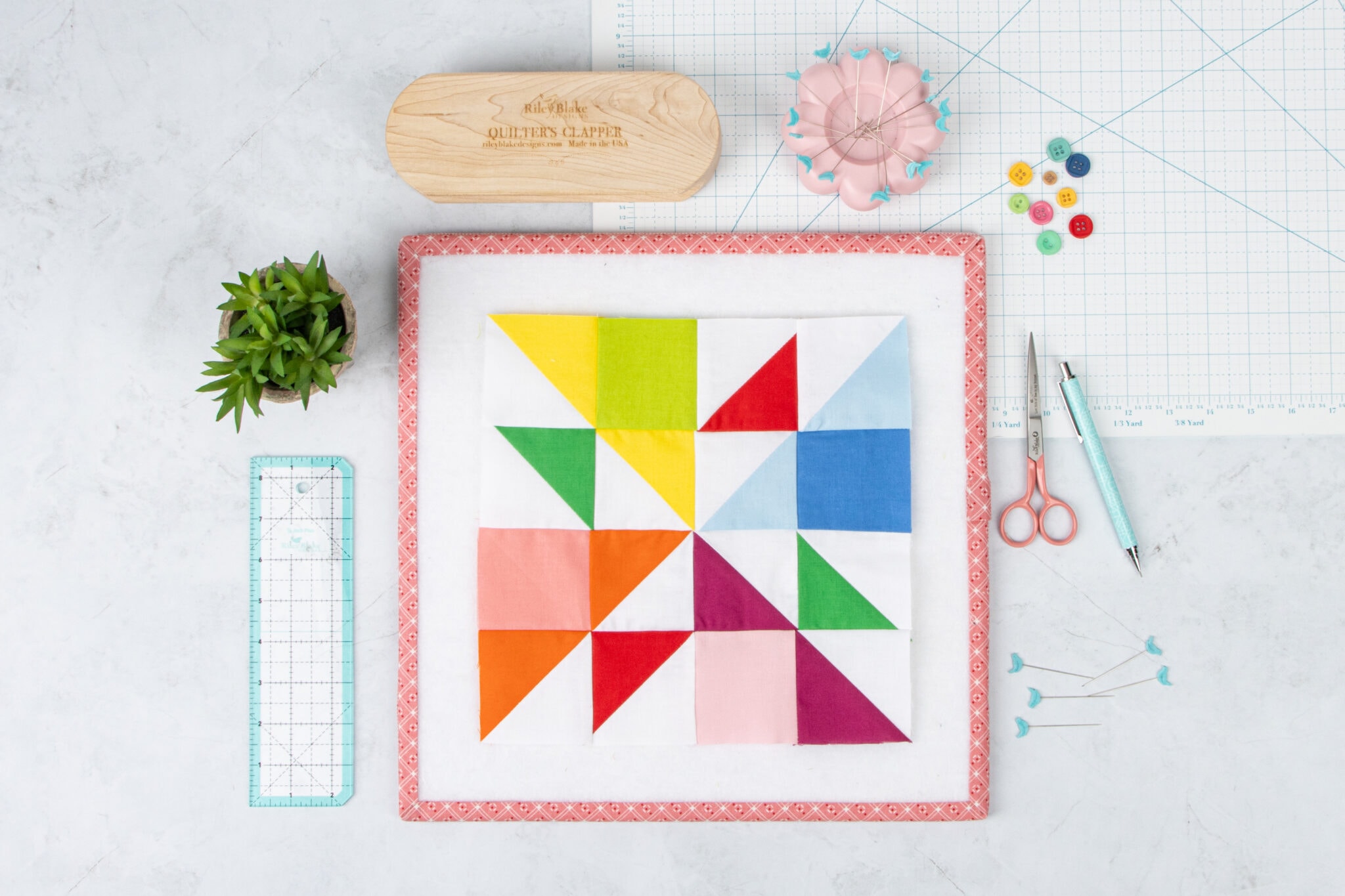 colorful, geometric quilt block on white table with sewing notios