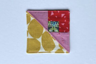 squares of pink, red and green fabric on white table with pins - construction steps of fabric bookmark
