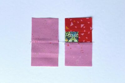 squares of pink, red and green fabric on white table with pins - construction steps of fabric bookmark