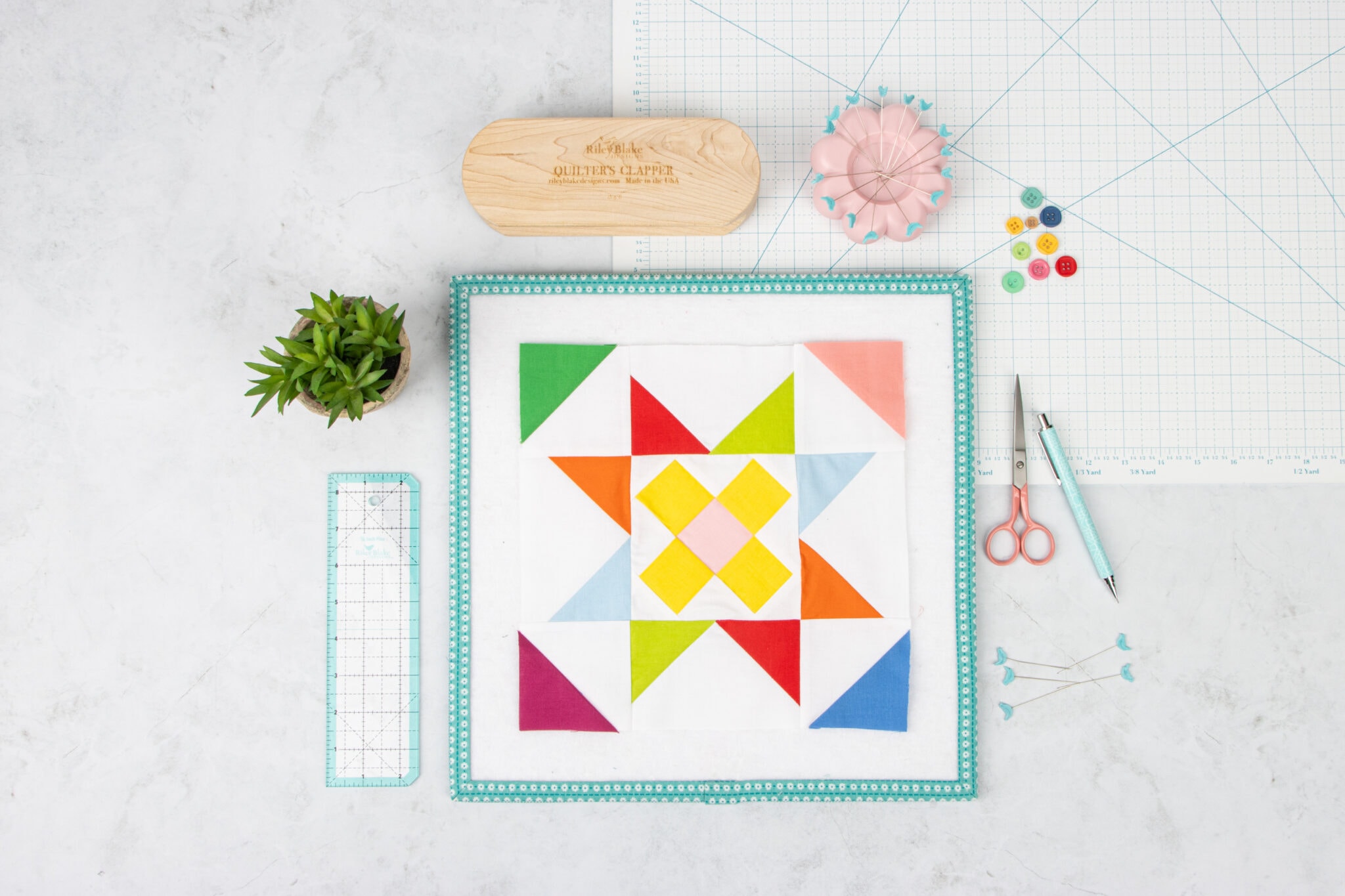 Colorful quilt block on white table with sewing notions