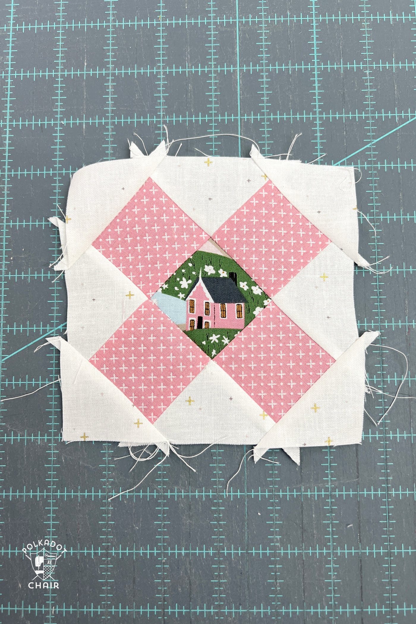 pink and white quilt block on blue cutting mat