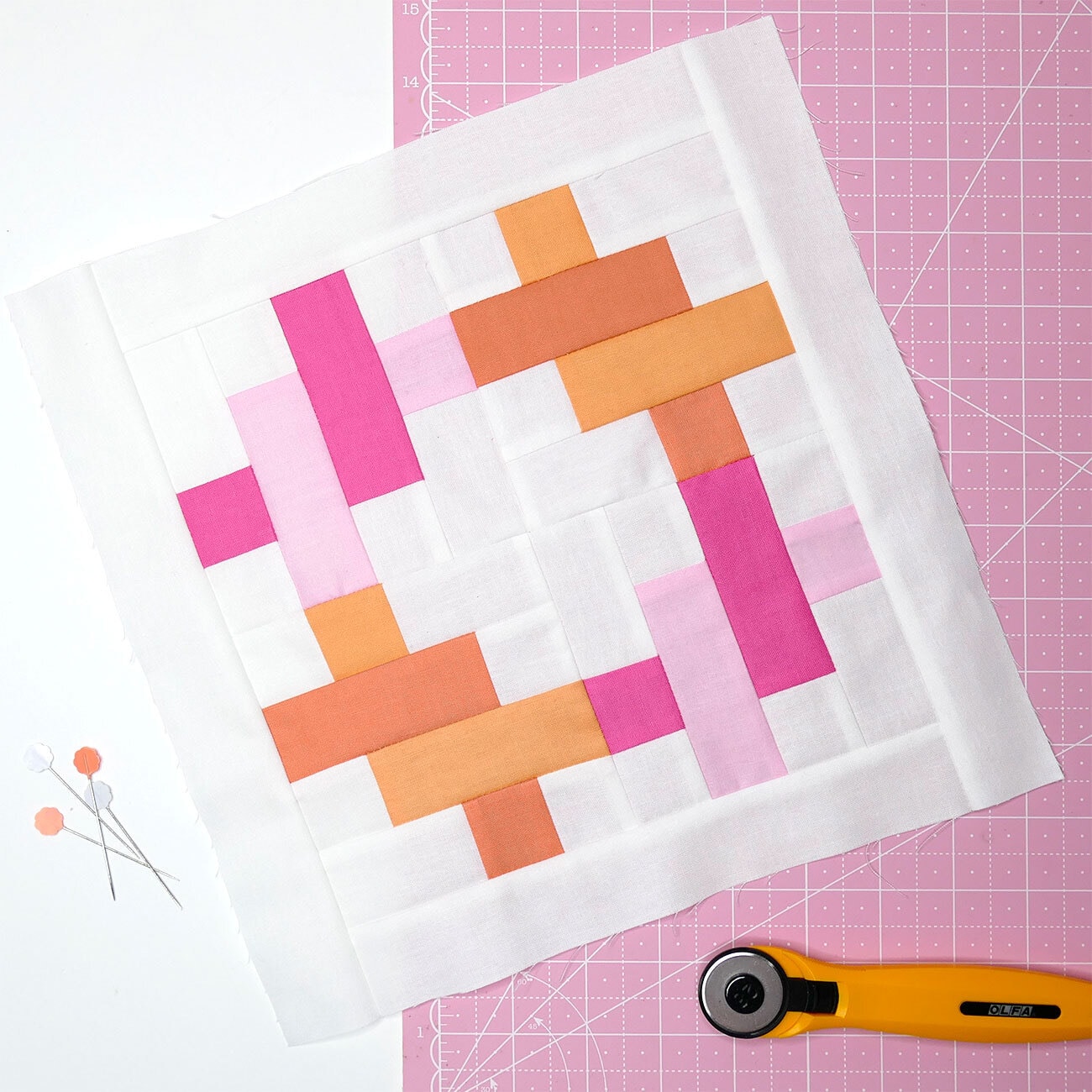 pink, white and orange quilt block on pink cutting mat