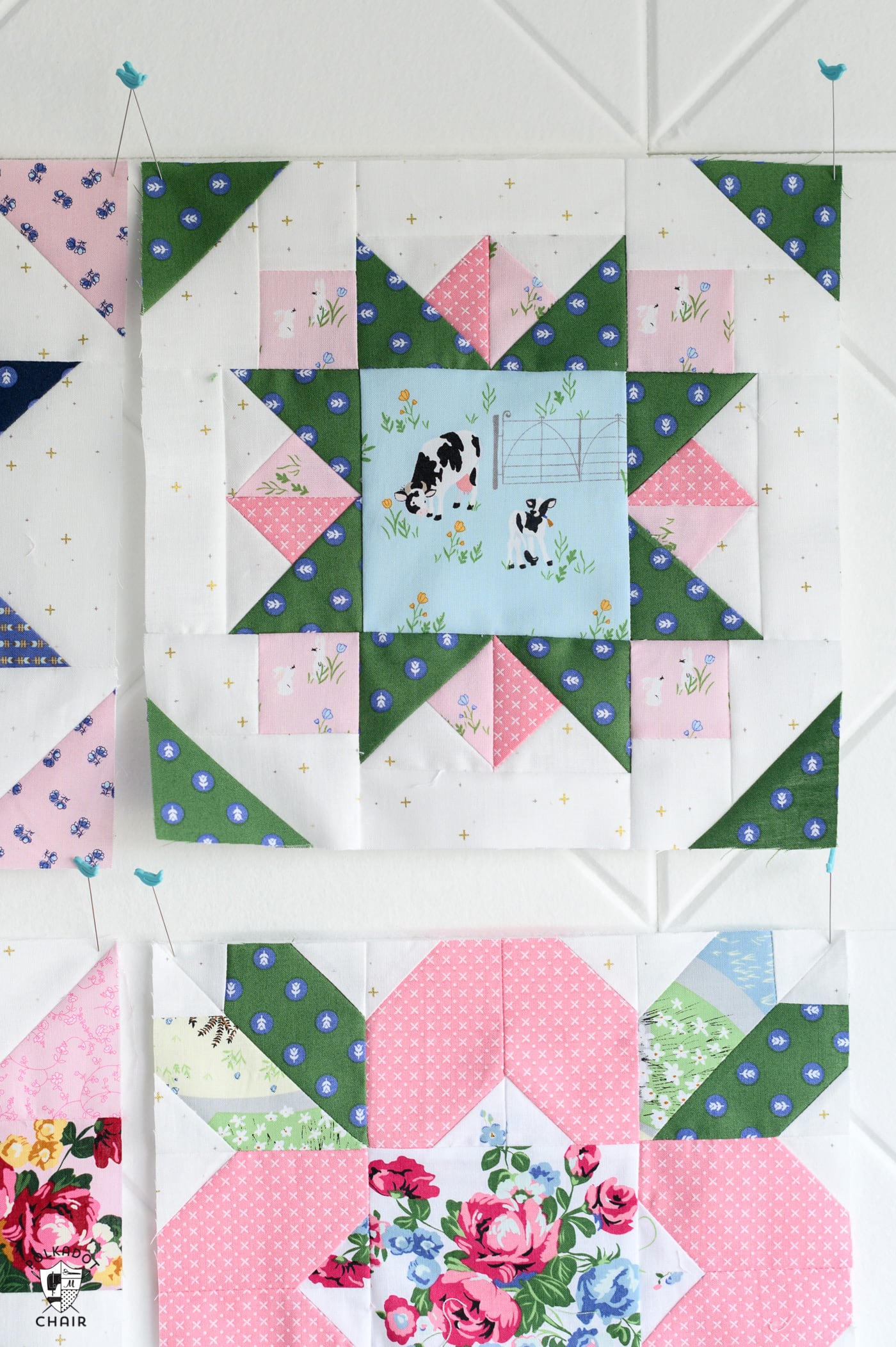 multiple pink and green and blue quilt blocks on white wall