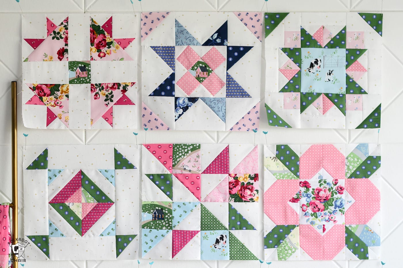 multiple pink and green and blue quilt blocks on white wall