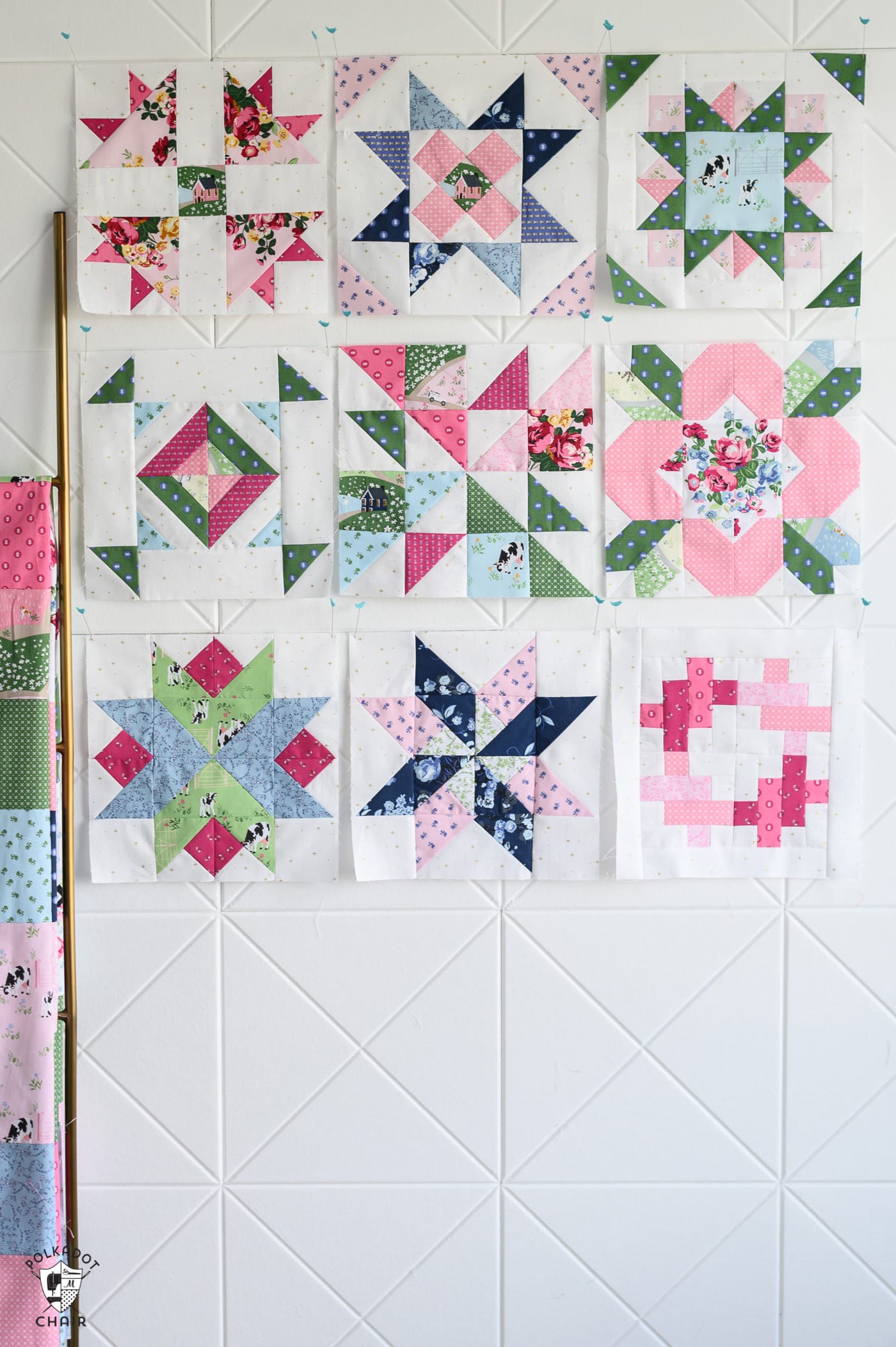 multiple pink and green and blue quilt blocks on white wall