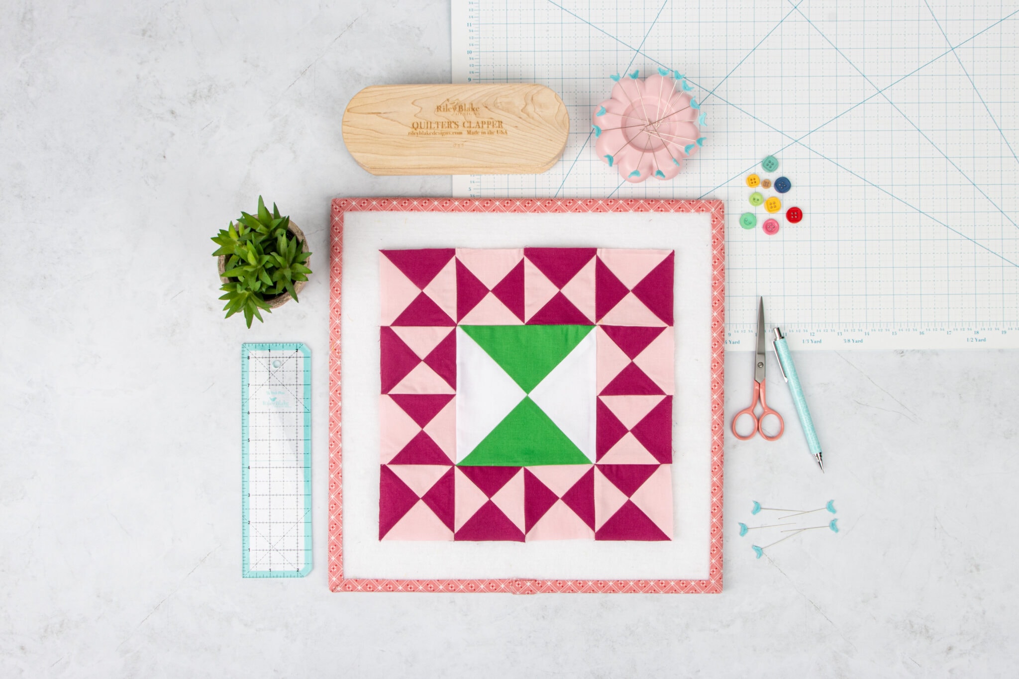 pink, white and green quilt block on table