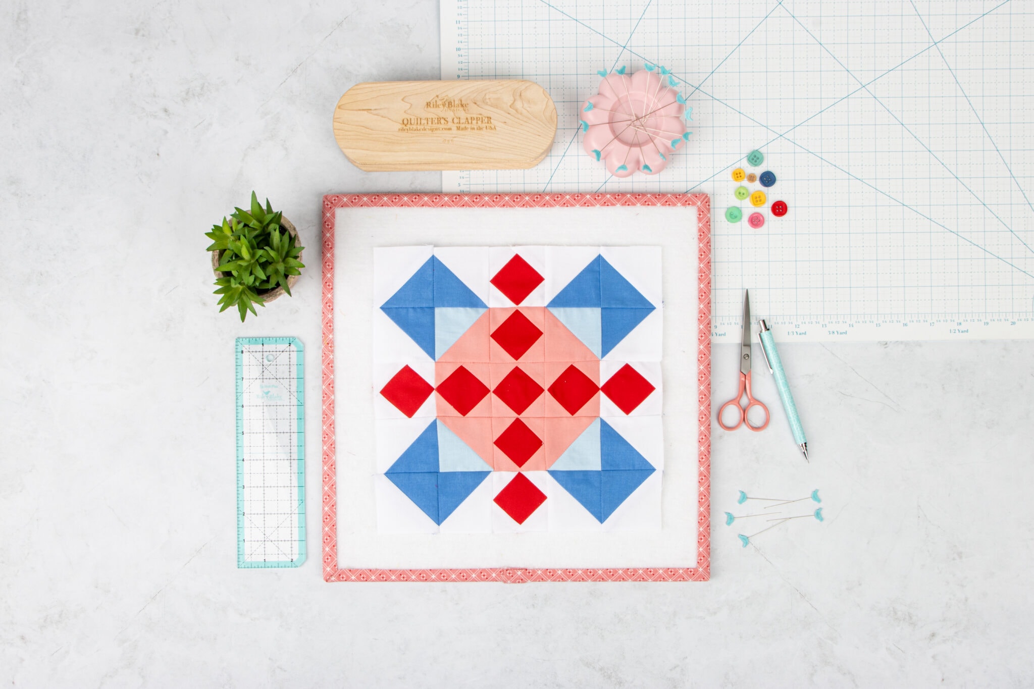 light blue and orange quilt block on white table