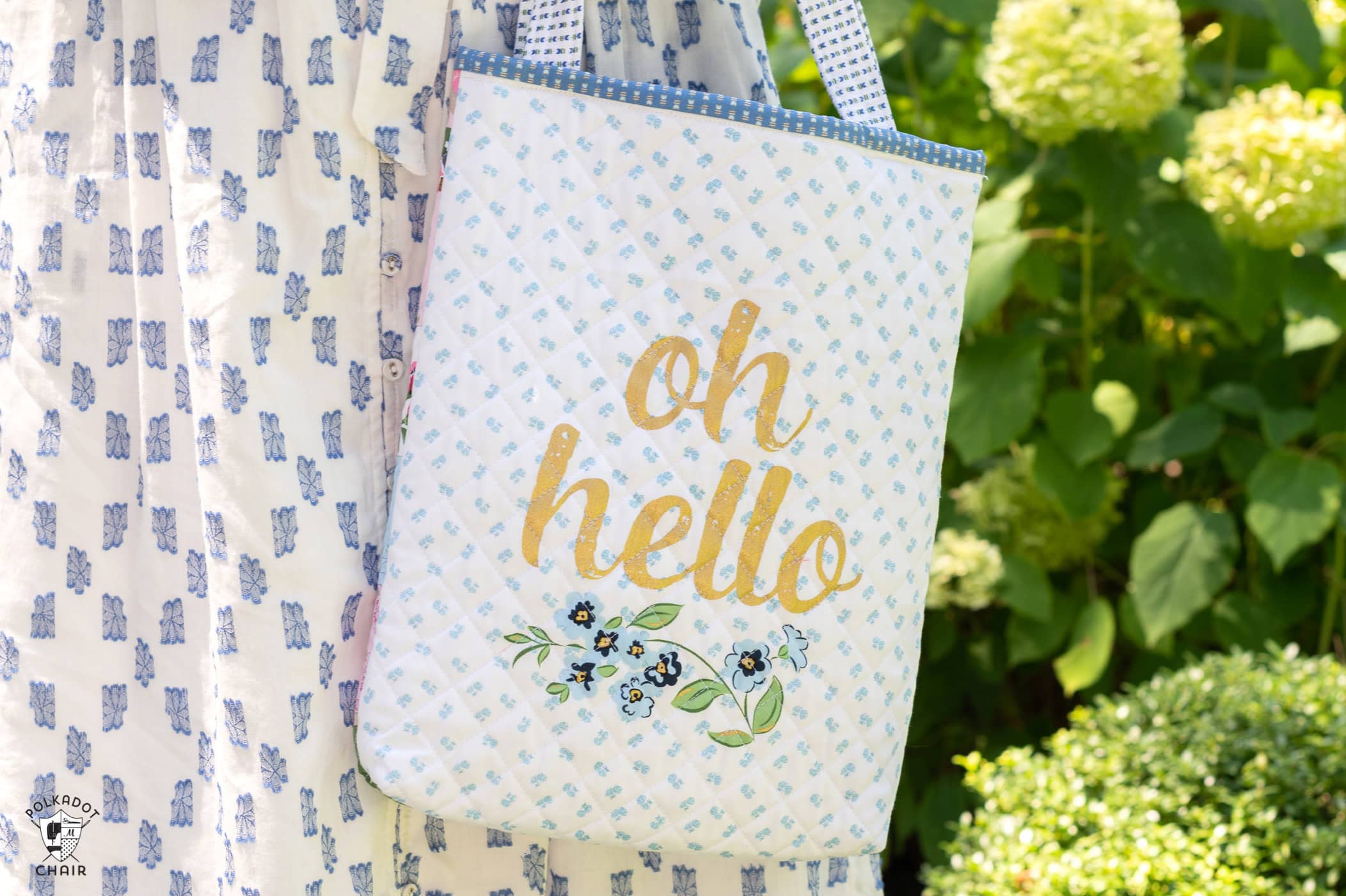 woman holding blue and white tote bag outdoors