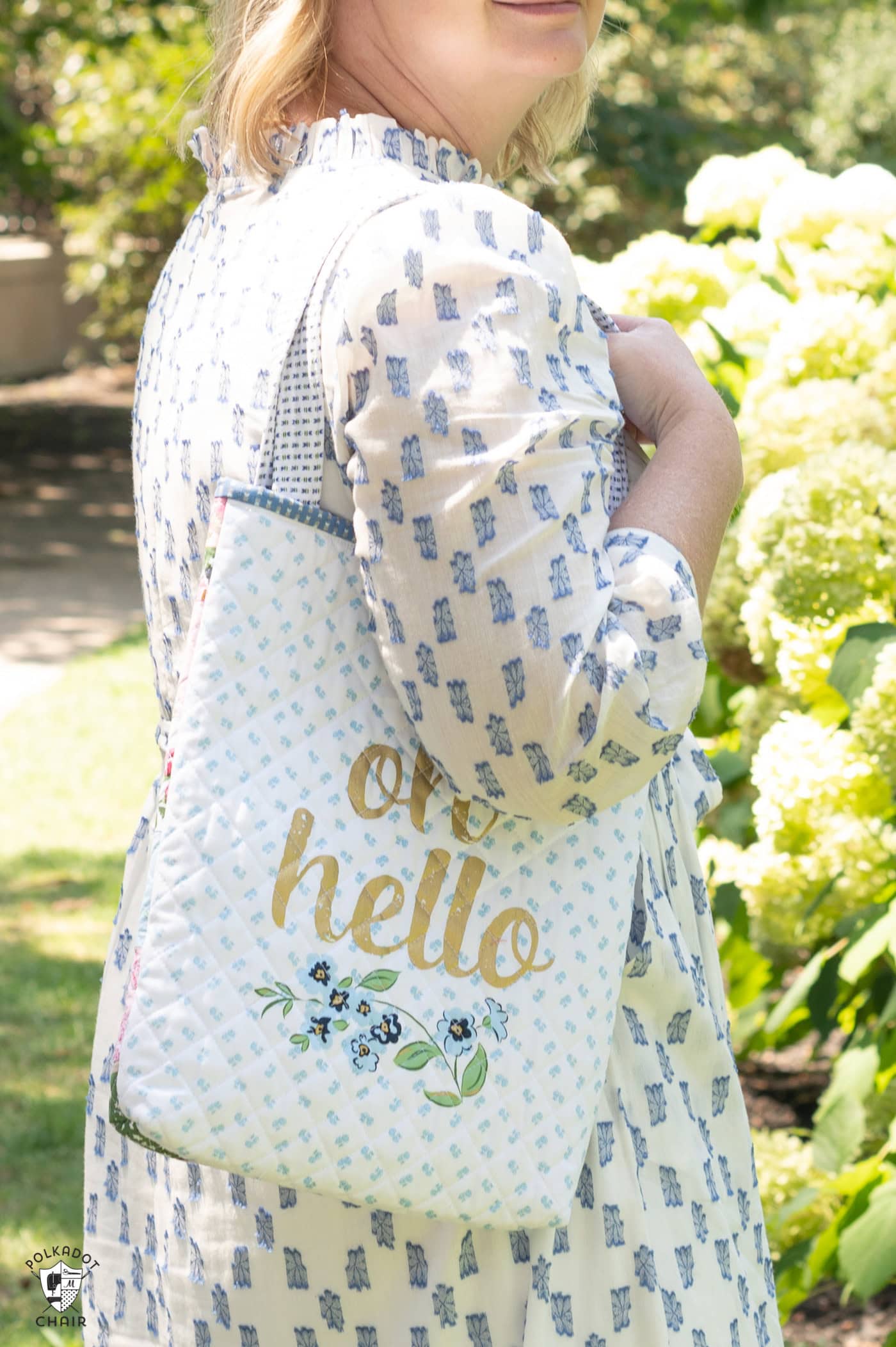 woman holding blue and white tote bag outdoors