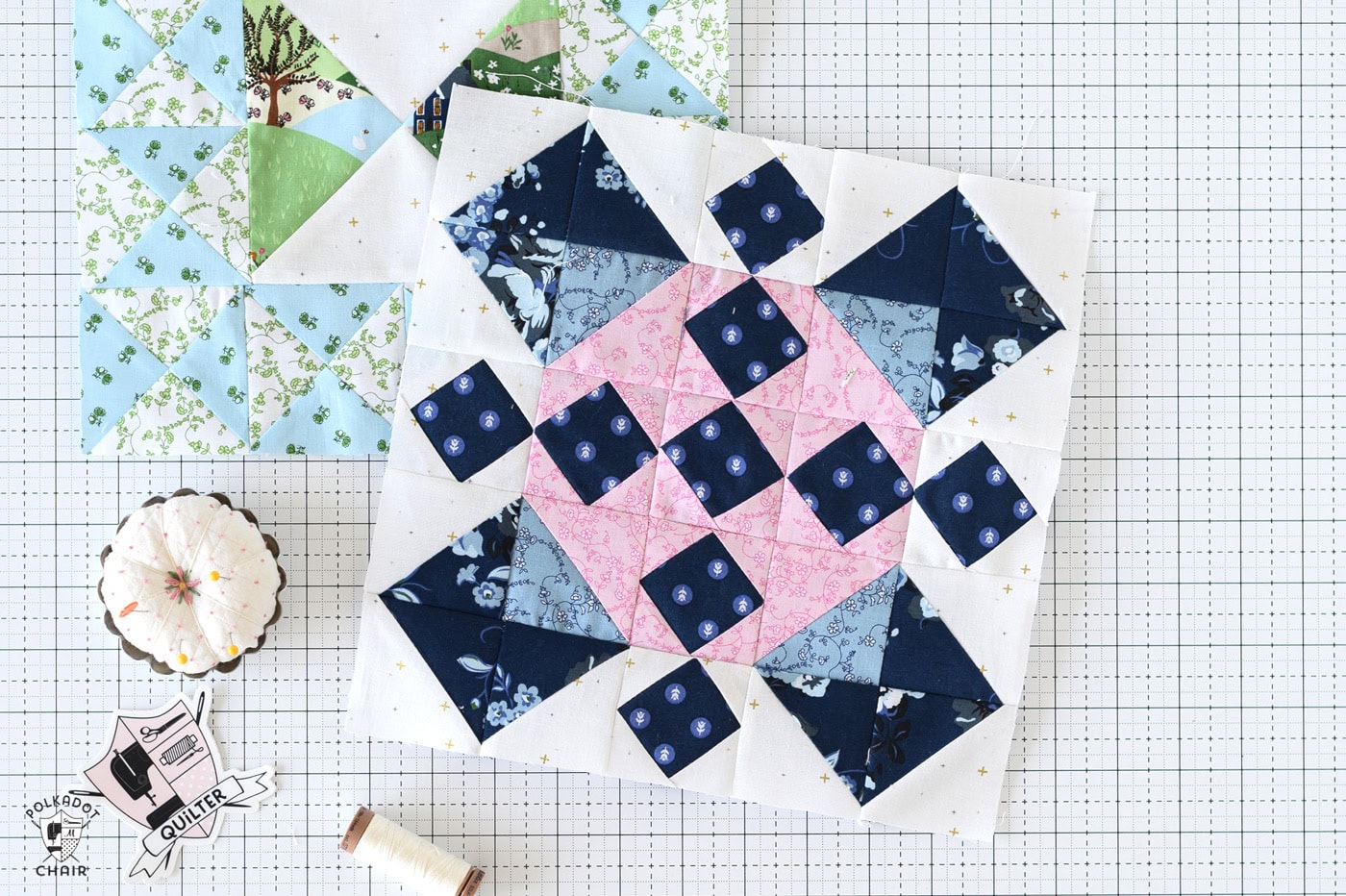 blue and pink quilt block on white cutting mat with sewing notions