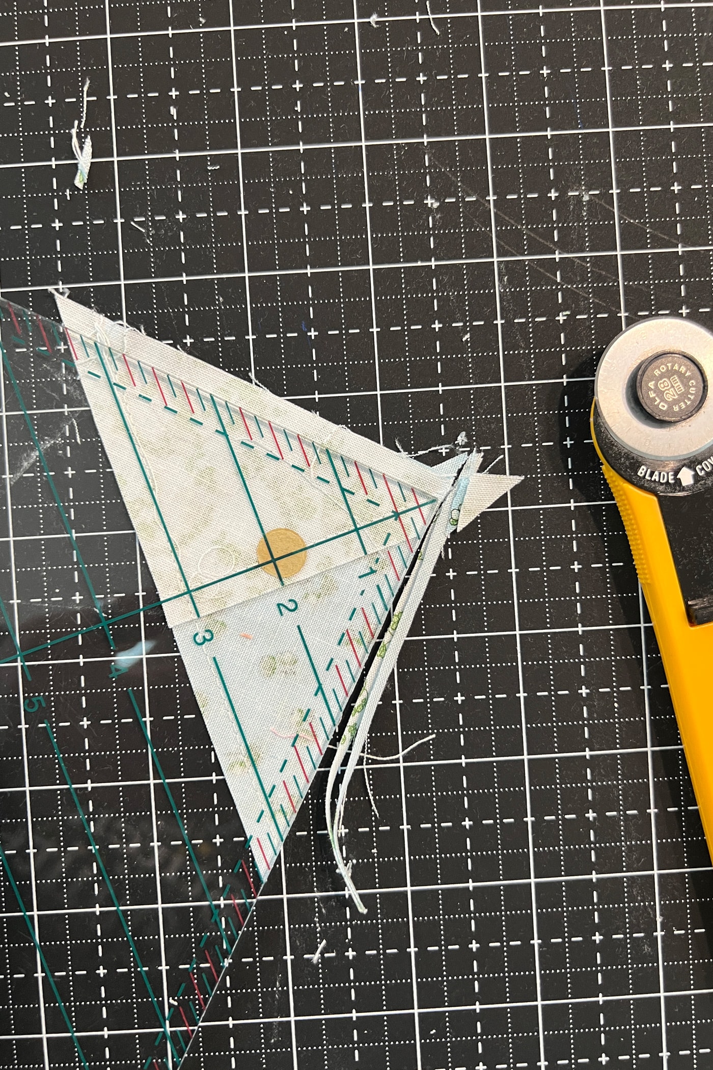 quilt block, ruler and rotary cutter on black cutting mat