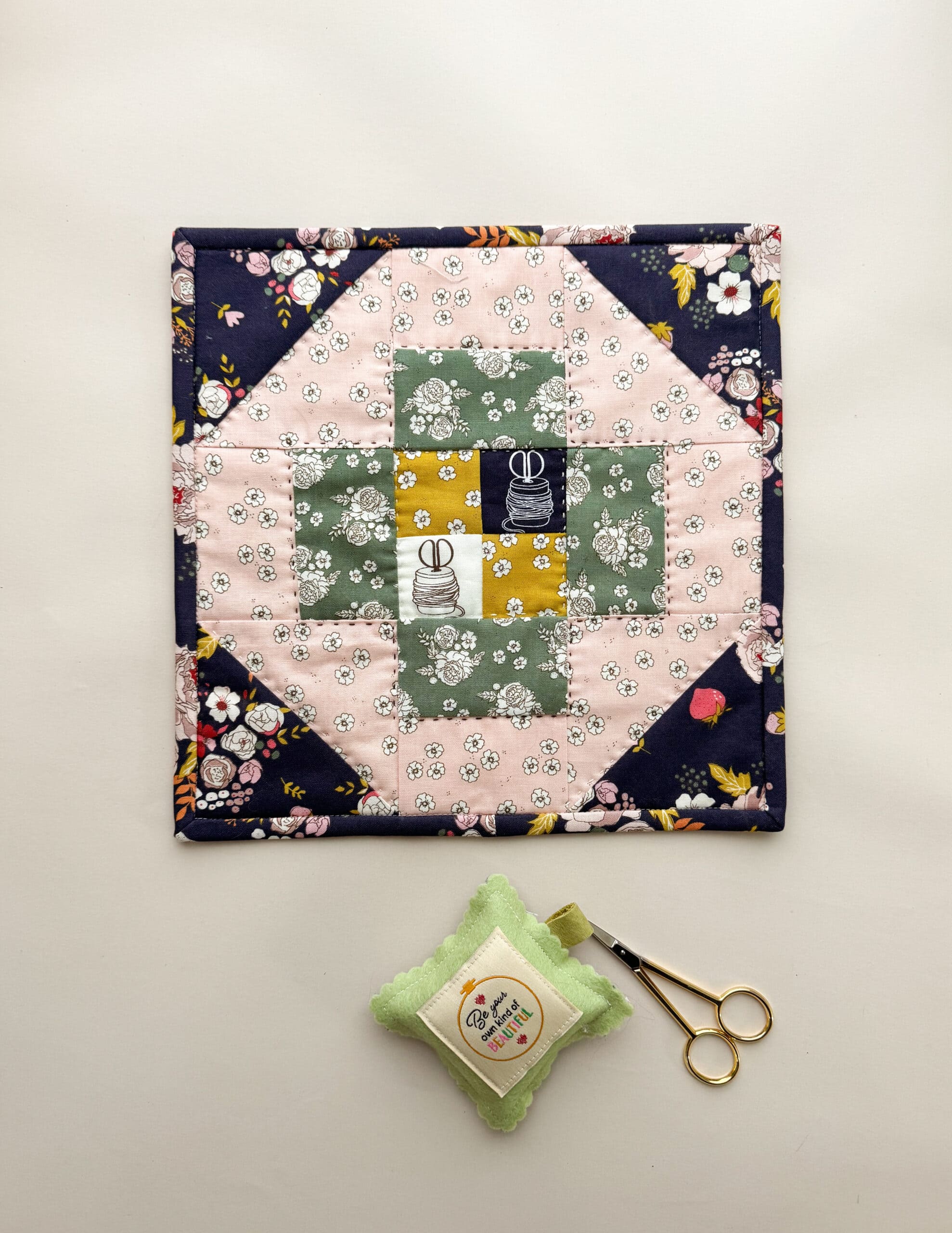 black, pink and green quilt block on cream table