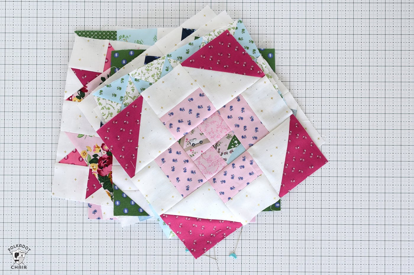 pink and red quilt block on white cutting mat with sewing notions