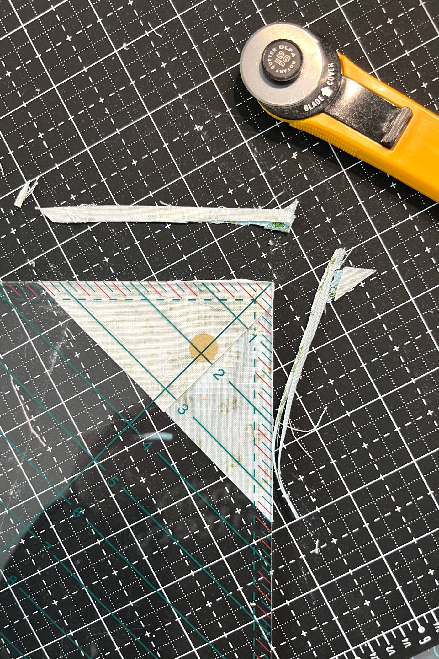 quilt block, ruler and rotary cutter on black cutting mat