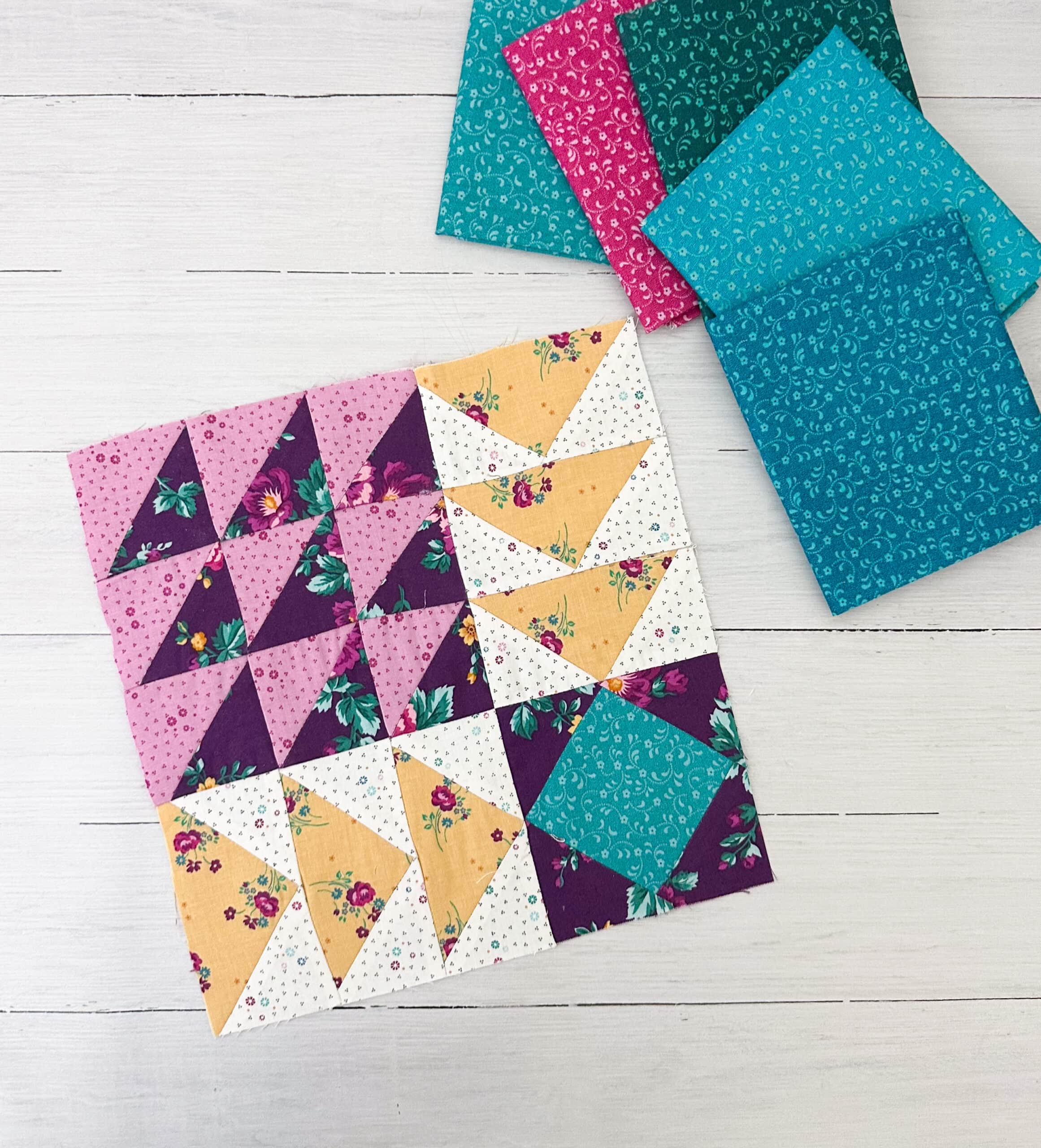Purple, yellow and teal quilt block on white wood table