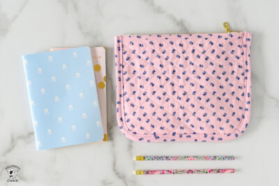 pink quilted zip pouch on white marble table with notebook and pencils