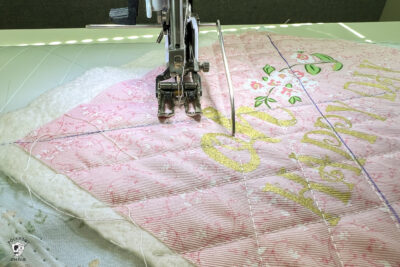 walking foot of sewing machine on top of pink fabric