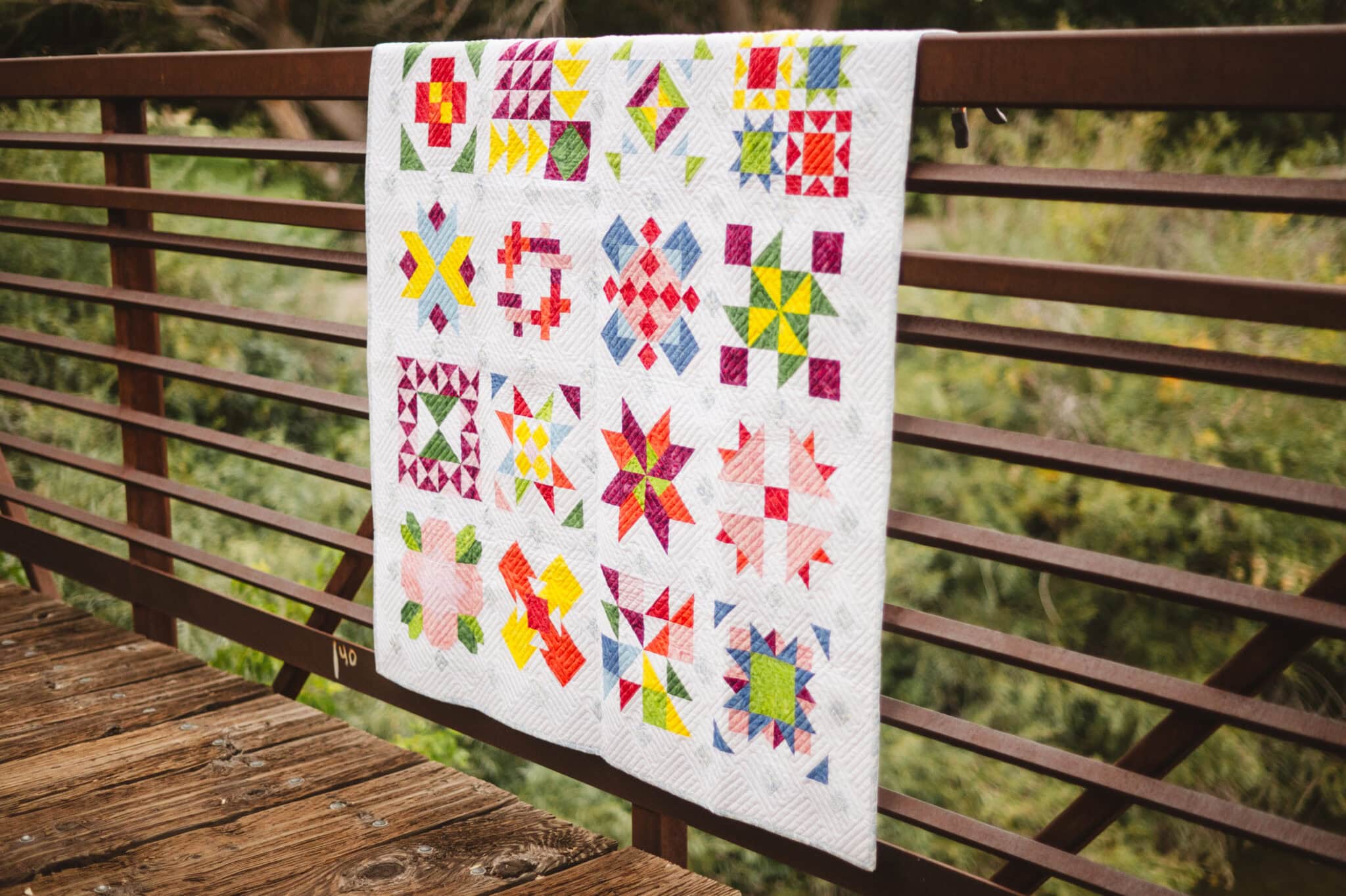 colorful sampler quilt outdoors on fence