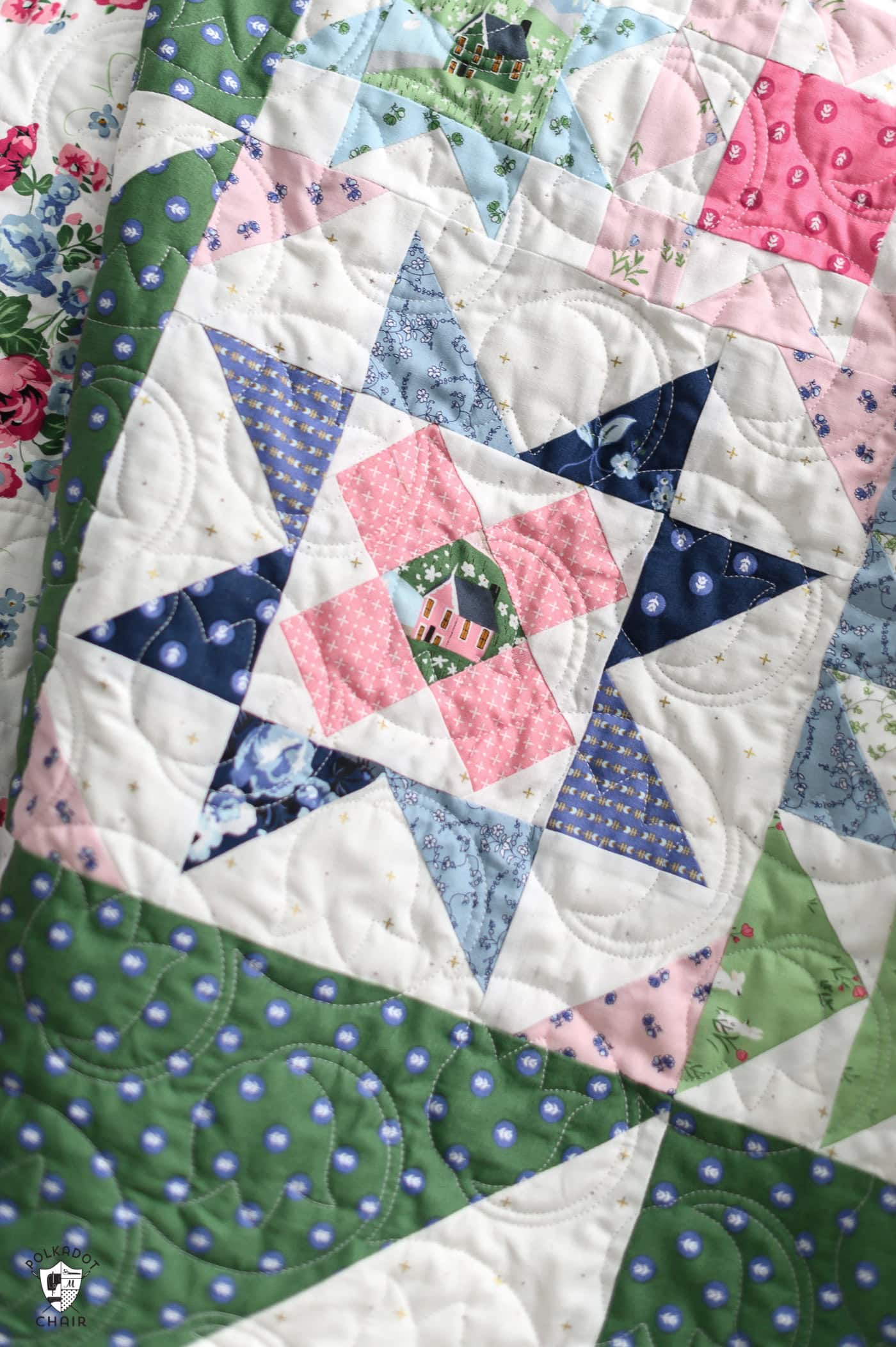 blue, green and pink quilt on bed in bright room
