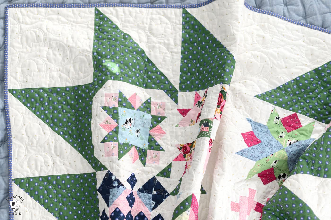 blue, green and pink quilt on bed in bright room