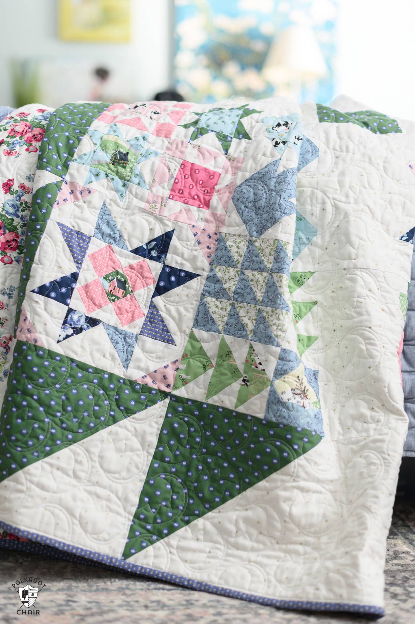 blue, green and pink quilt on bed in bright room