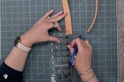 image of hand marking location on leather bag strap