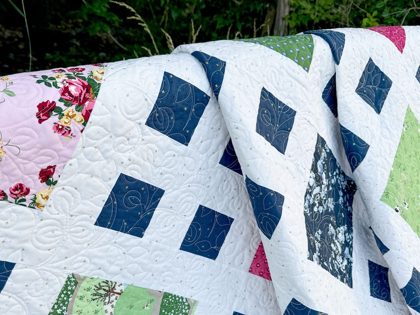 close up of patchwork quilt in pink, white navy & green