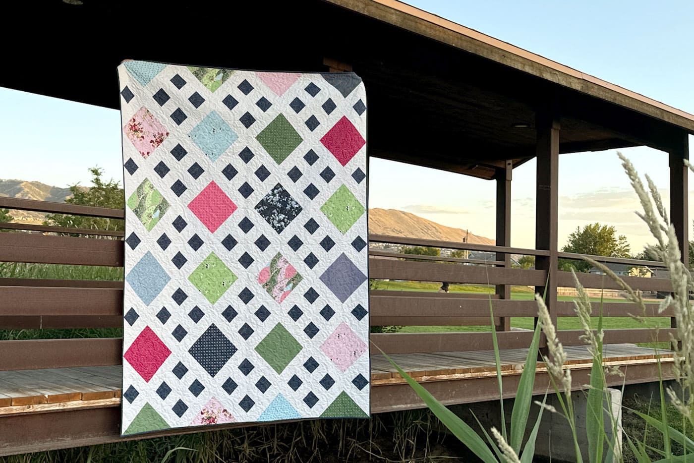 close up of patchwork quilt in pink, white navy & green