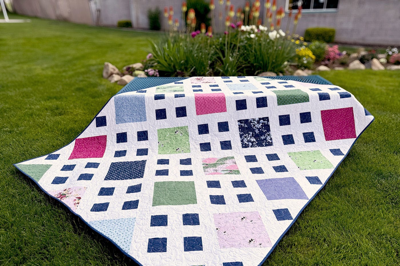 close up of patchwork quilt in pink, white navy & green