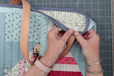 hand attaching hardware to tote bag