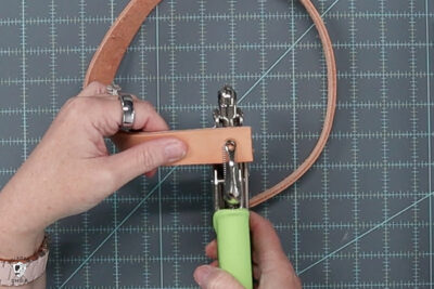 image of hole being punched in leather strap