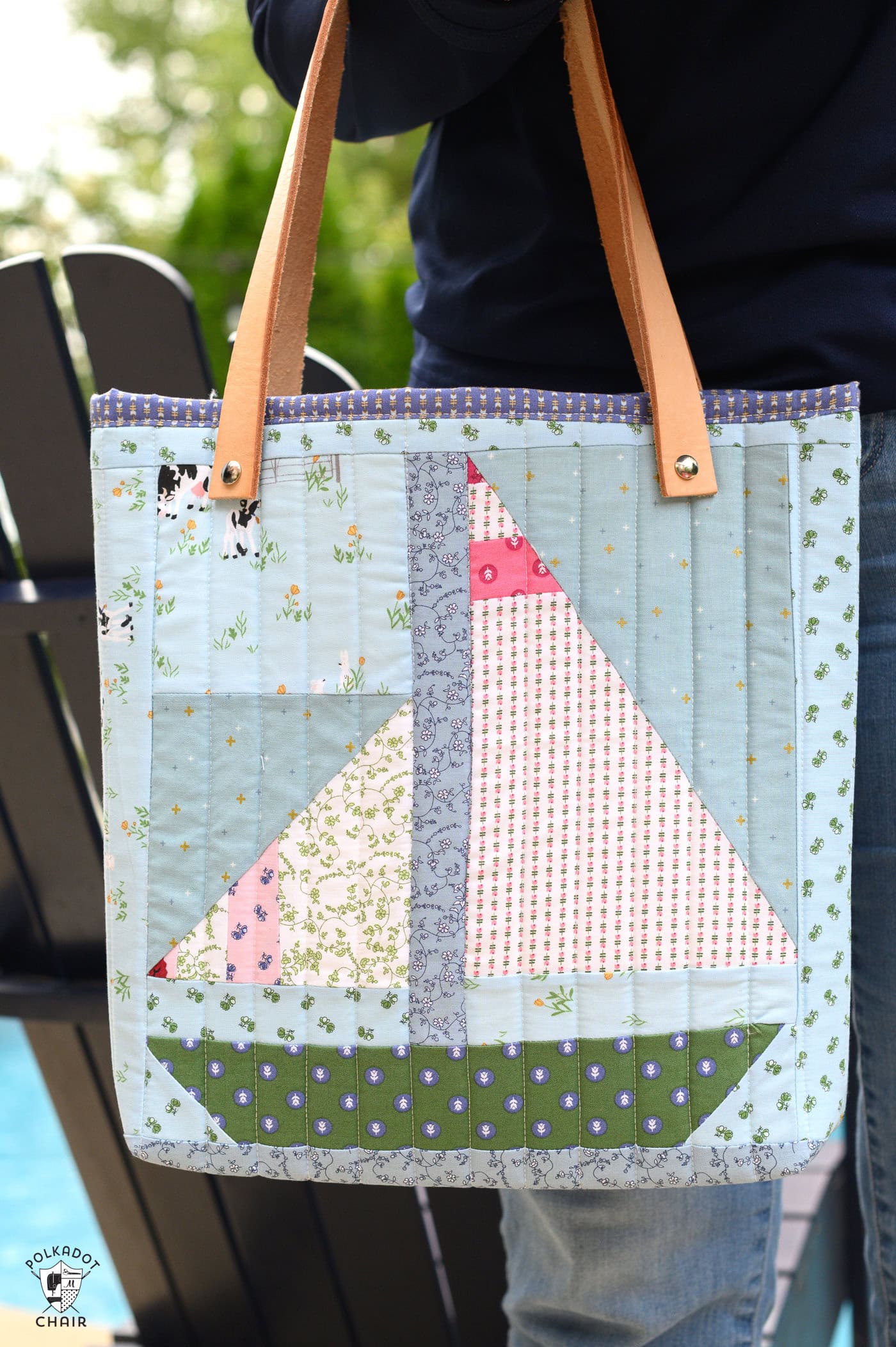 quilted tote bag on navy chair next to pool