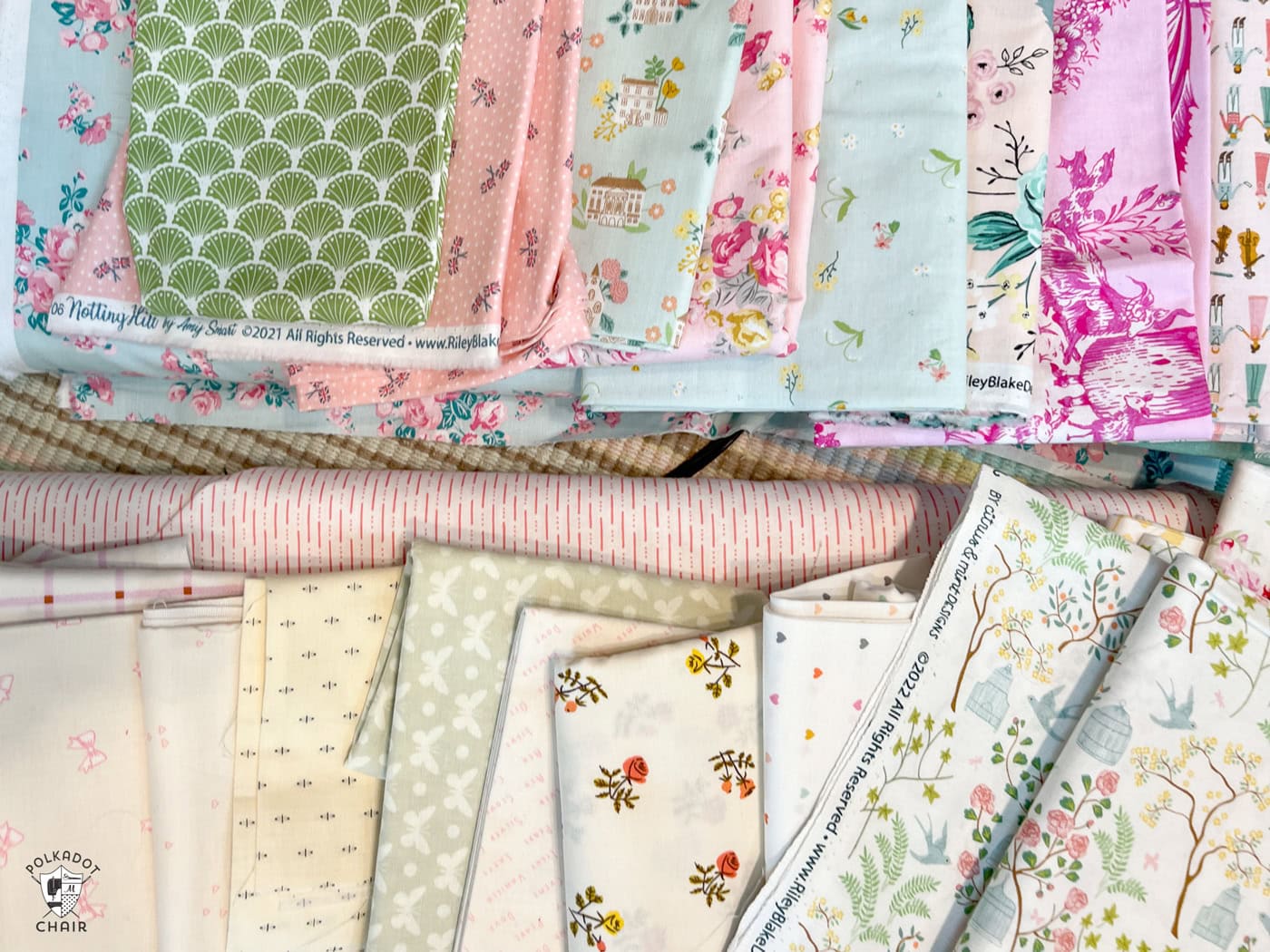 stack of pink, ivory, blue and green fabrics on table