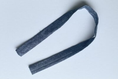 blue fabric strip on white table with pins and thread