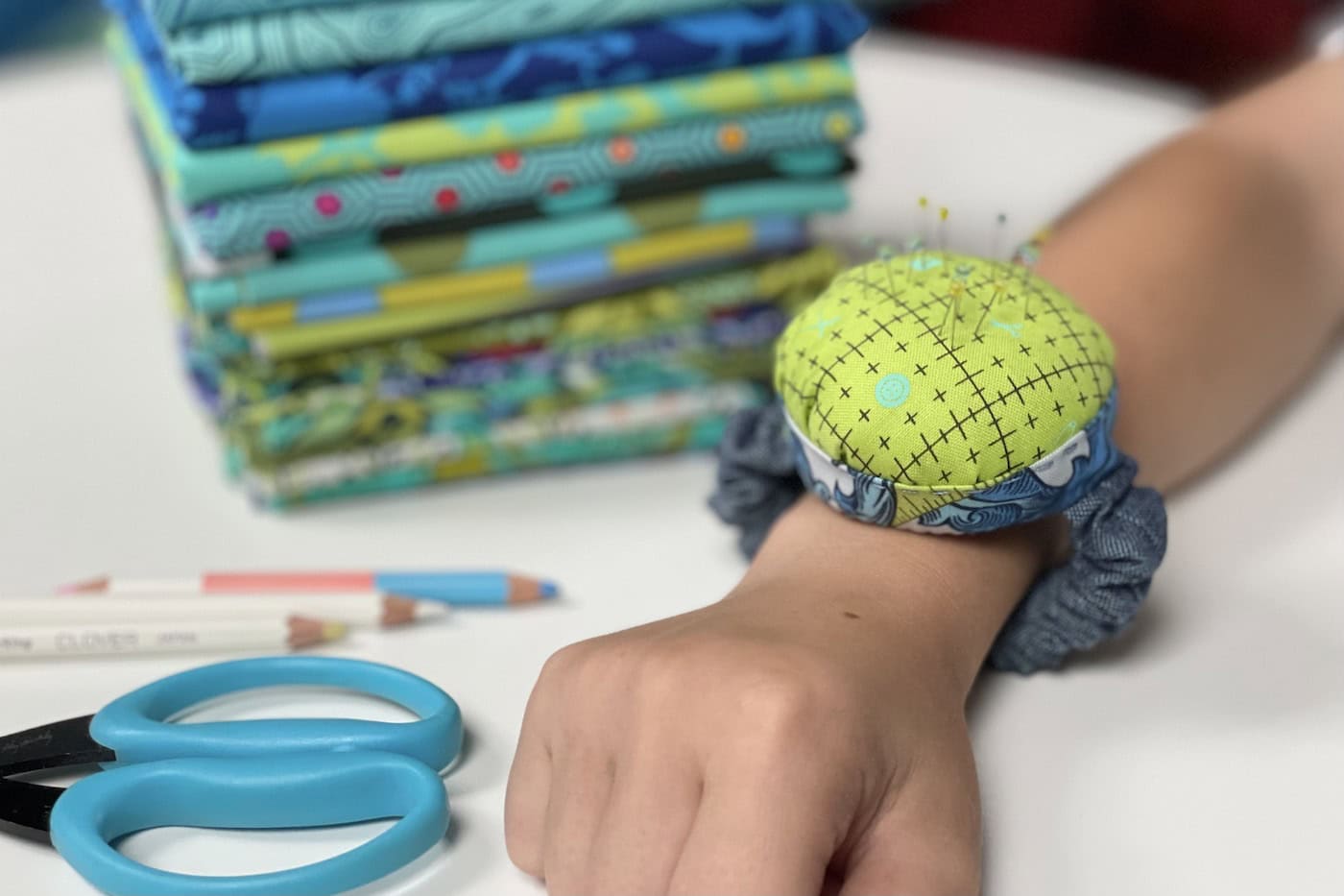 Blue and green pincushion on wrist