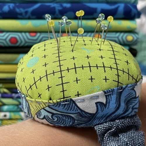 Blue and green pincushion on wrist