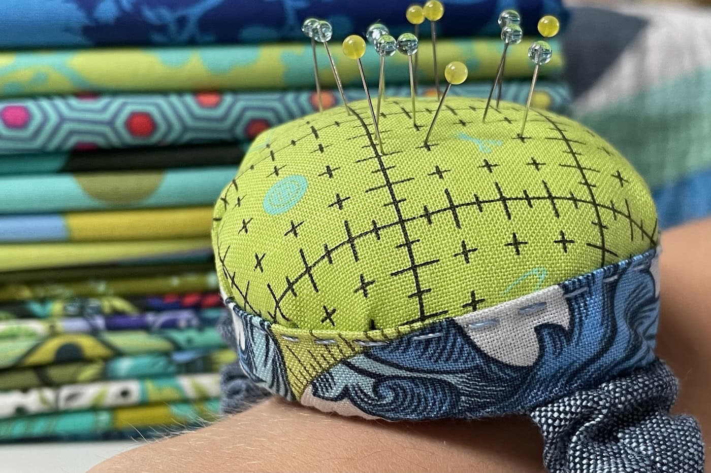 Blue and green pincushion on wrist