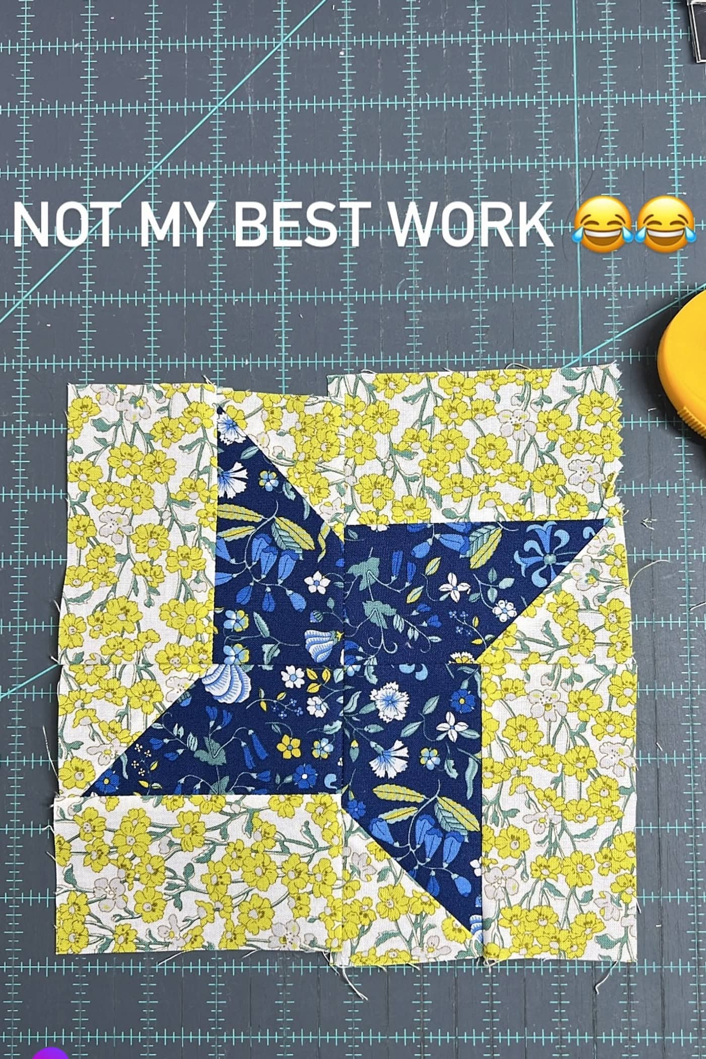 navy and yellow quilt block on blue cutting mat