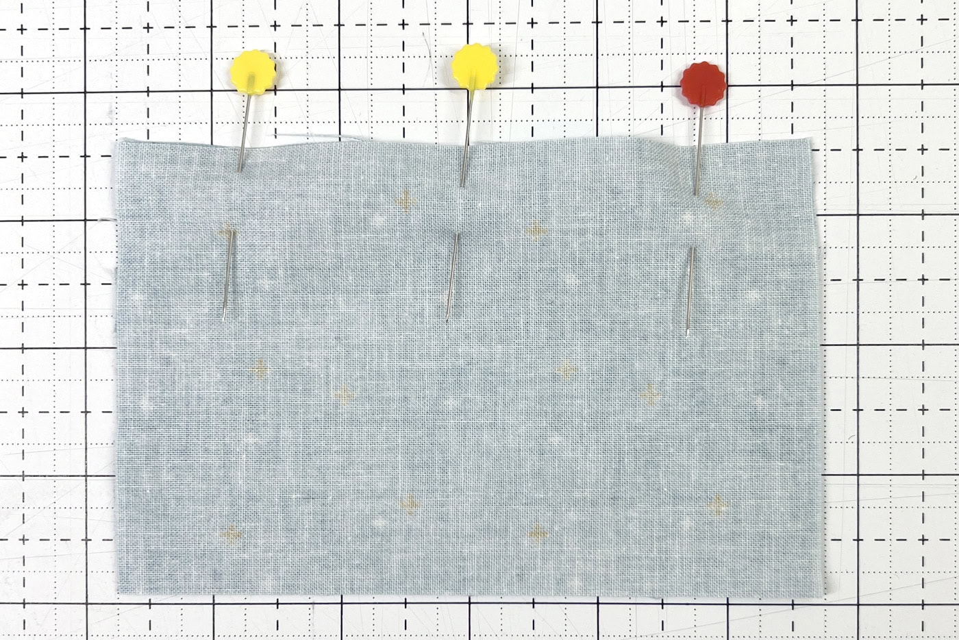 pins in fabric on white cutting mat