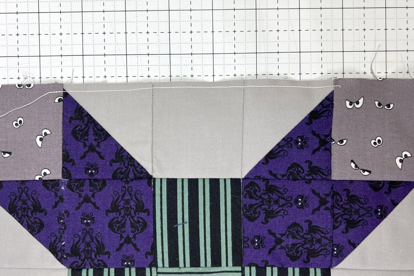 stitching line close up on gray and purple quilt block
