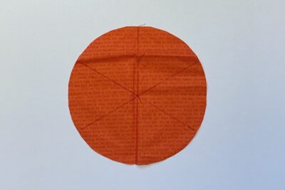 orange circle of fabric on white table, during construction process to turn it into a pumpkin