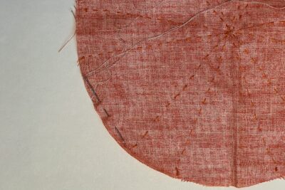 orange circle of fabric on white table, during construction process to turn it into a pumpkin