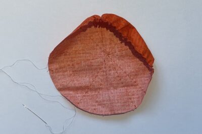 orange circle of fabric on white table, during construction process to turn it into a pumpkin