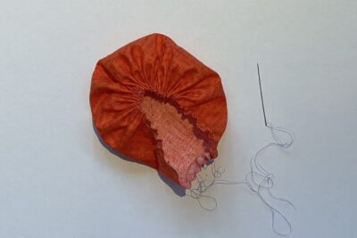 orange circle of fabric on white table, during construction process to turn it into a pumpkin