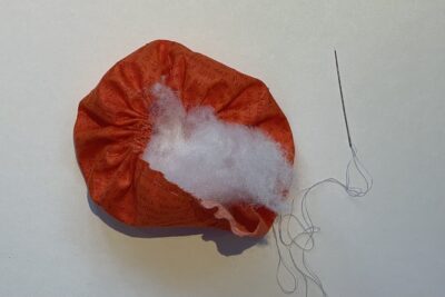 orange circle of fabric on white table, during construction process to turn it into a pumpkin