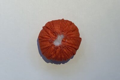 orange circle of fabric on white table, during construction process to turn it into a pumpkin