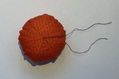 orange circle of fabric on white table, during construction process to turn it into a pumpkin