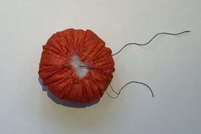 orange circle of fabric on white table, during construction process to turn it into a pumpkin