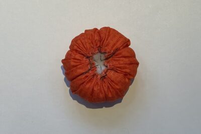 orange circle of fabric on white table, during construction process to turn it into a pumpkin