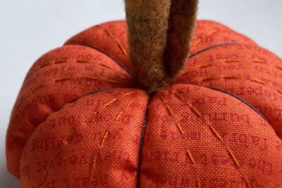 orange circle of fabric on white table, during construction process to turn it into a pumpkin with brown felt stem